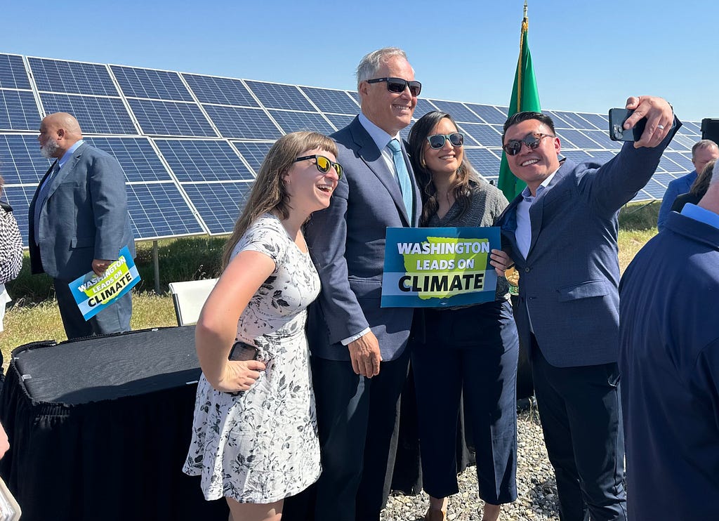 Photo of Sen. Joe Nguyễn taking a selfie with the governor and two women, all wearing sunglasses and smiling brightly. One woman holds a sign that says “Washington leads on climate.”