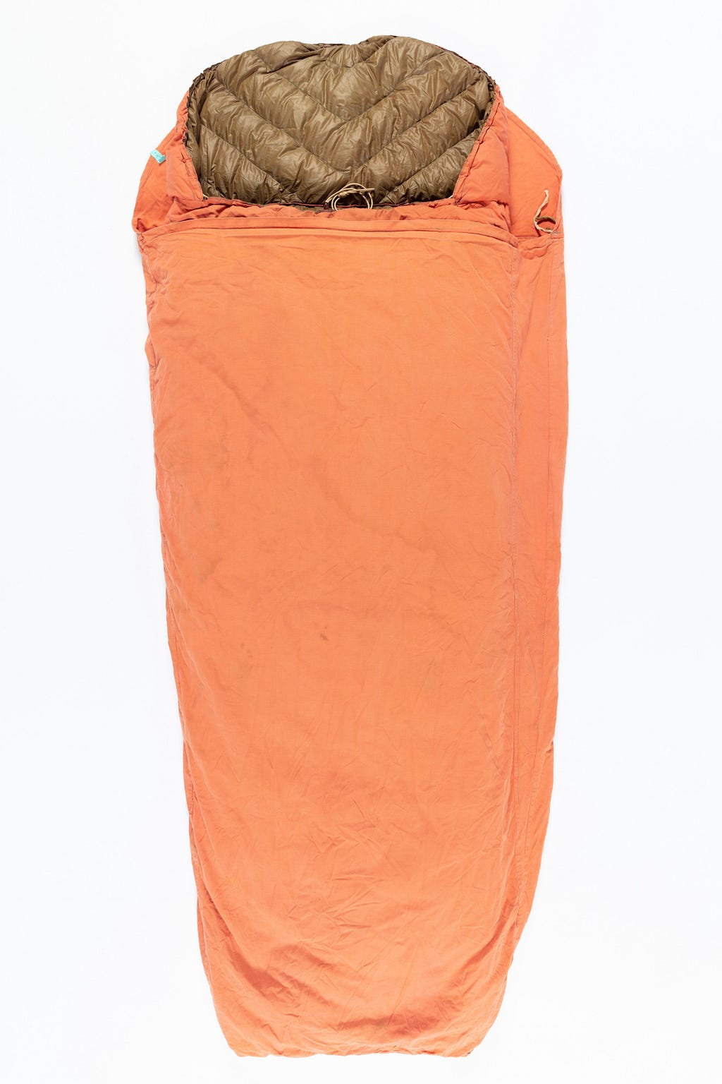 Orange cotton cover over a puffy brown sleeping bag. The material looks like canvas and is a bright safety orange but faded from age.