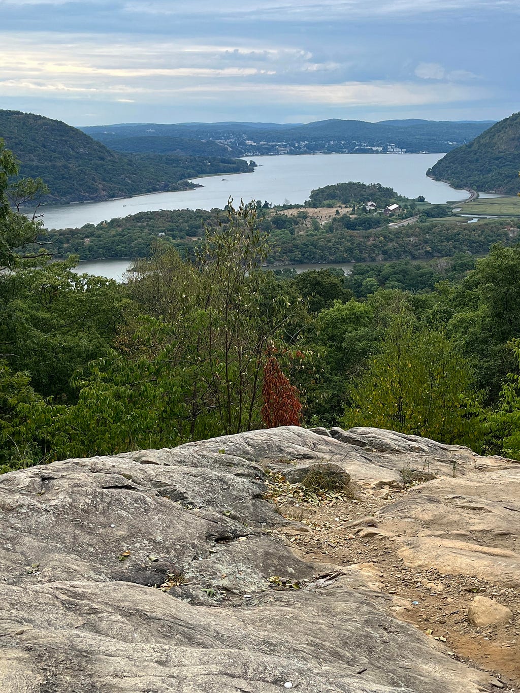 View of a lake in a valley, with lush green landscape, from a rocky out-cropping on which the photographer stands.