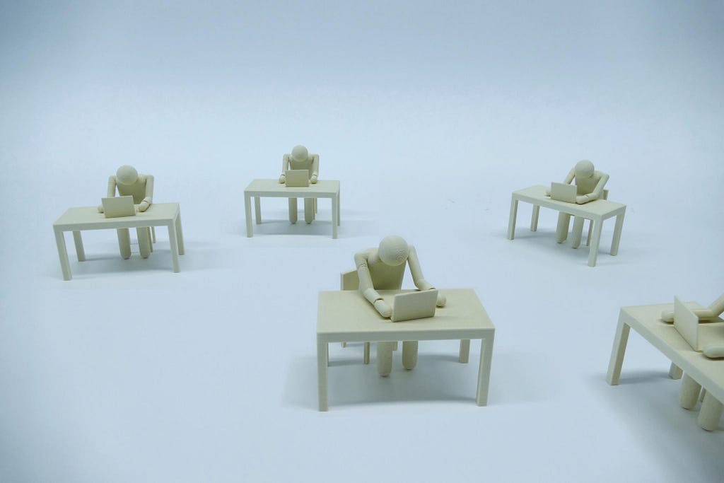 several wooden figures sitting at desks looking at laptops