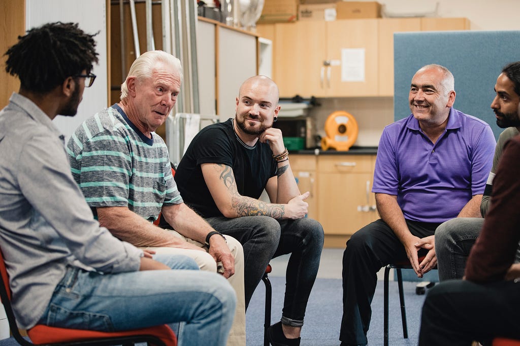 Group of men sat talking together in a mental health support group.