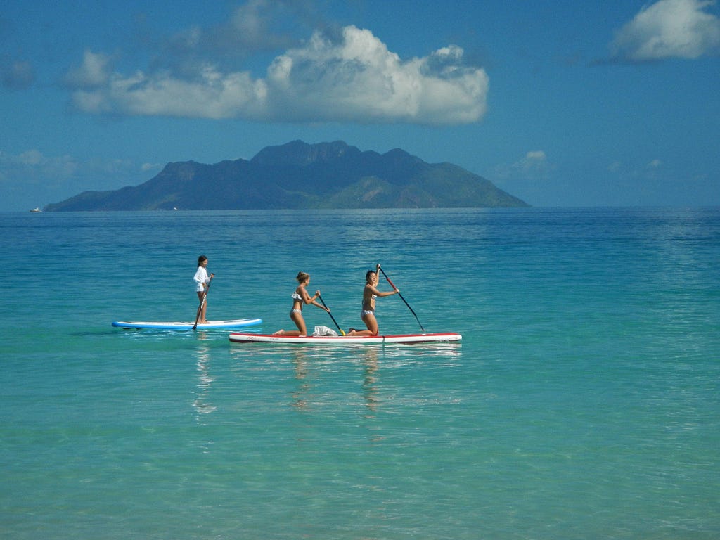 children stand-up-paddleboard off Beau Vallon beach on Mahé in the Seychelles. © April Orcutt