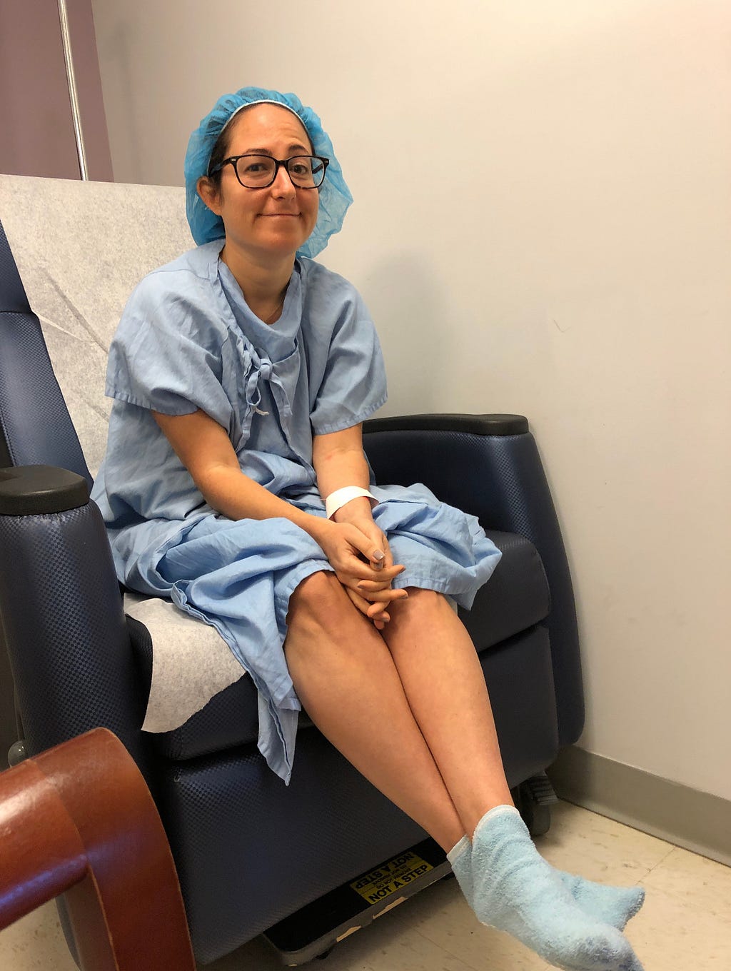 Woman sitting in a doctor’s office in a hospital gown