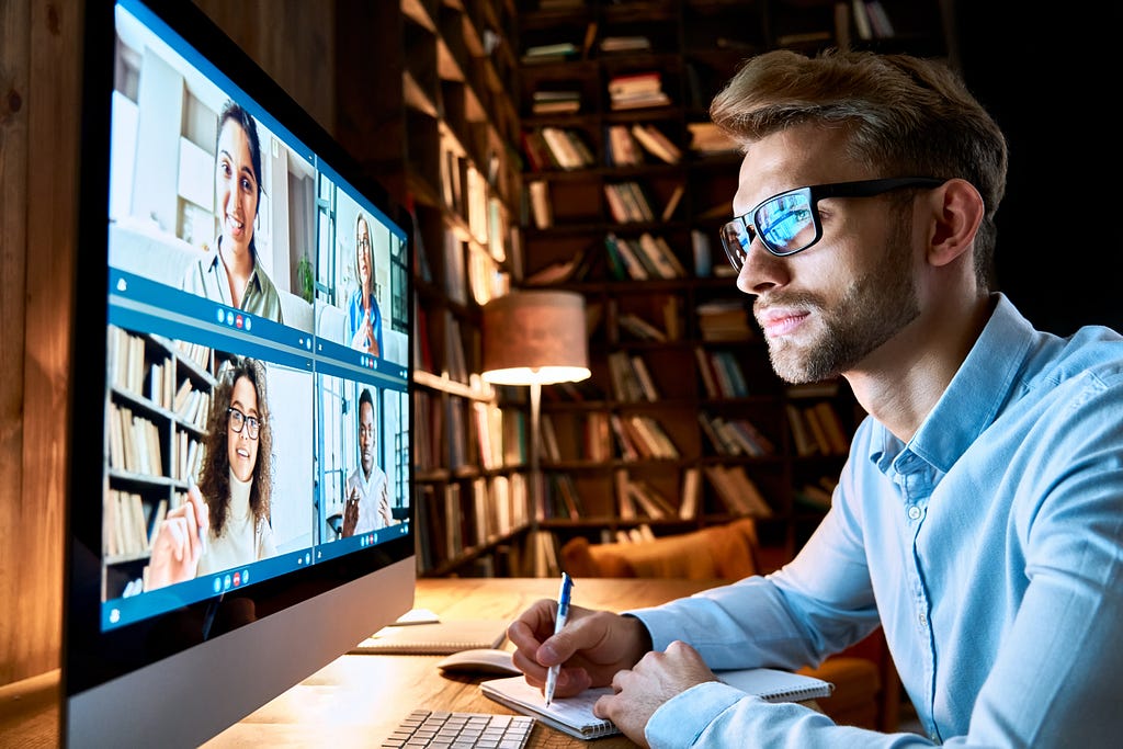 An employee works from home securely and sitting in front of a monitor screen at an online meeting