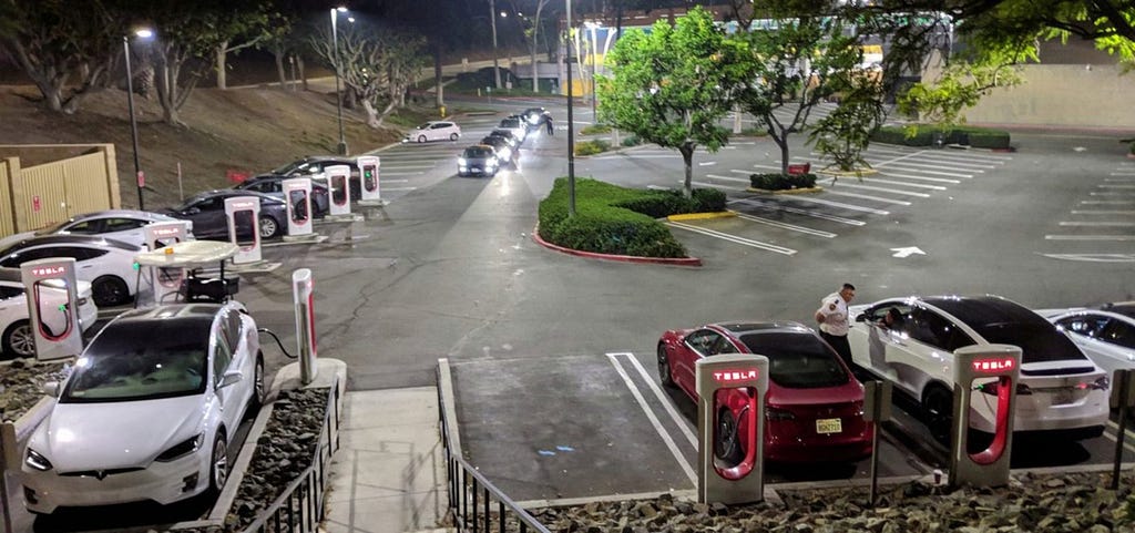 Teslas queuing at night at a Supercharger hub