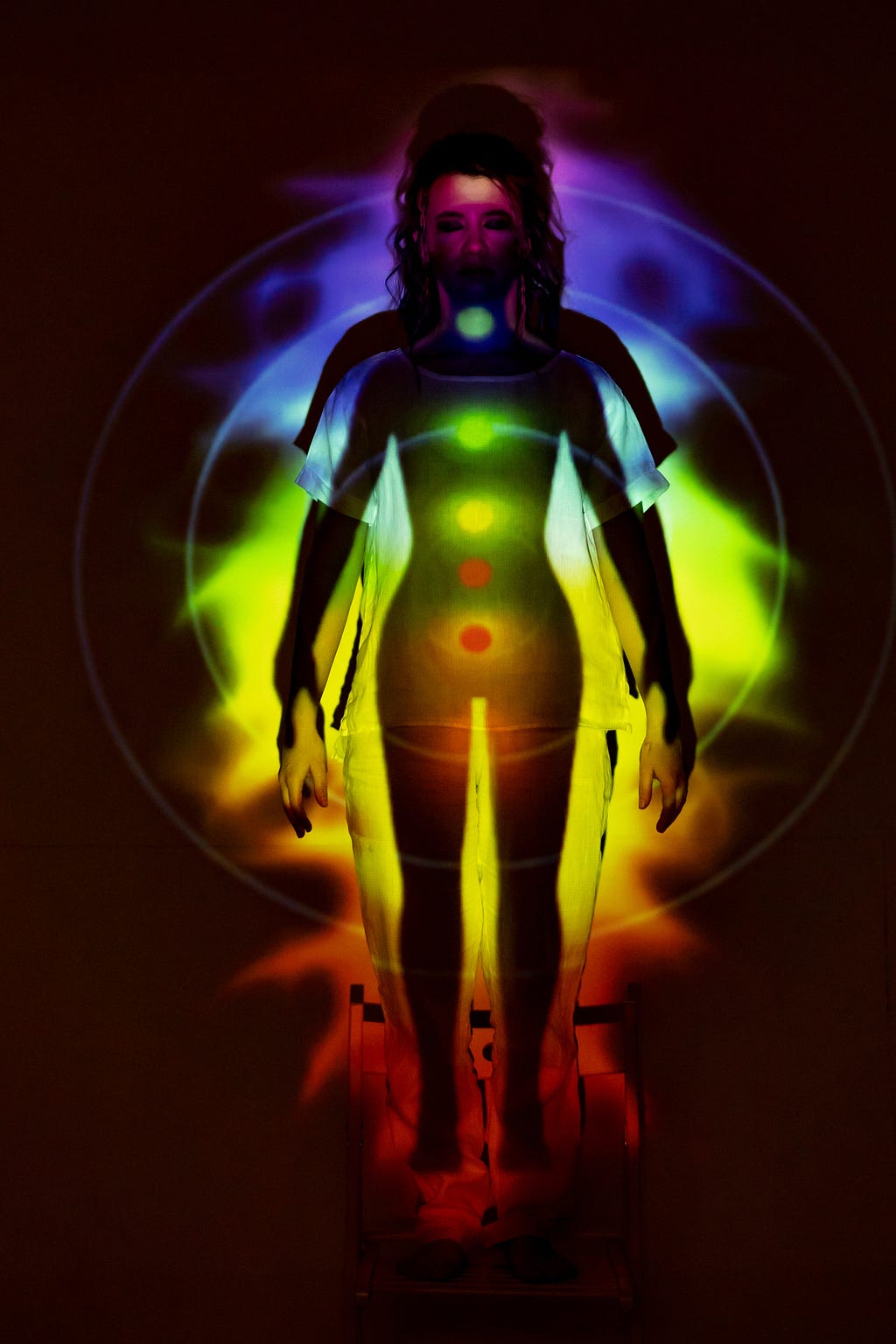 This is a picture of a female showing the aura. We can see a multi-coloured light surrounding the body of this female. The light is oval-shaped. We can also see the subtle seven chakras(energy centres). This is a multi-coloured picture of a human aura.