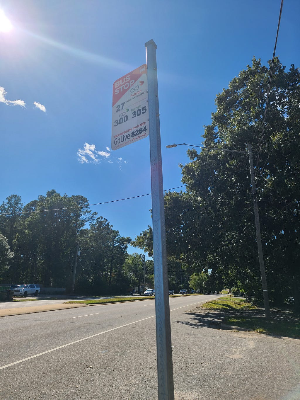 a bus stop sign with trees in the background