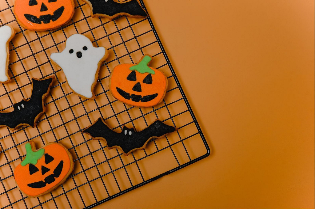 Halloween cookies on a cooling rack with orange background.
