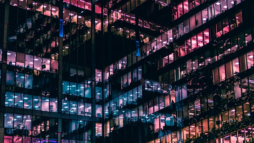 An office building lit up inside in hues of blue and pink