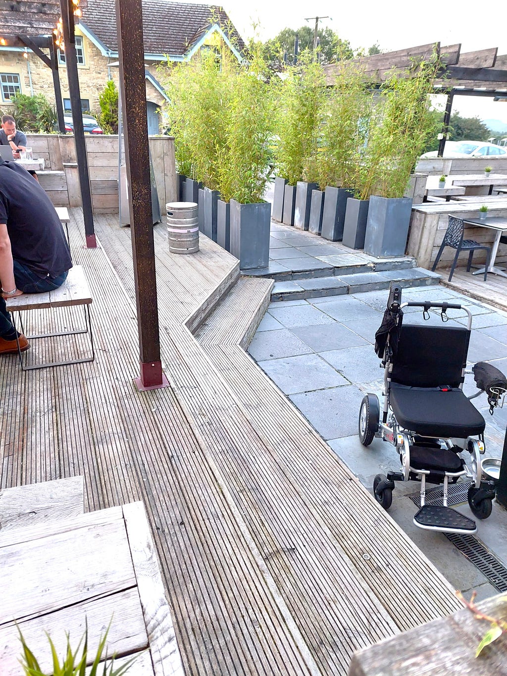 the outside deck area of the bar at the Derwent Manor Hotel. The decking is made of tongue and groove wood planks. The steps are topped and faced with the same material. This makes it hard to see where a step is. The steps lead down to a slate area, which also has a couple of steps. These are also hard to see, as they are also faced and topped with the same material.