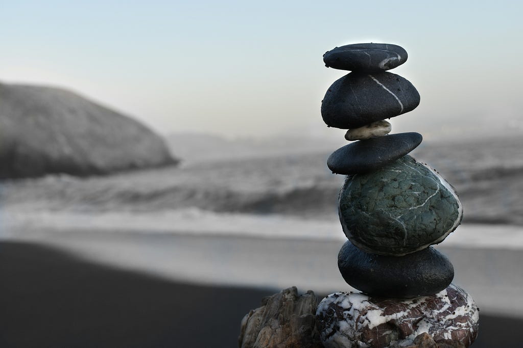 A stack of smooth, round stones balanced carefully upon one another, creating a cairn, commonly found on beachside settings