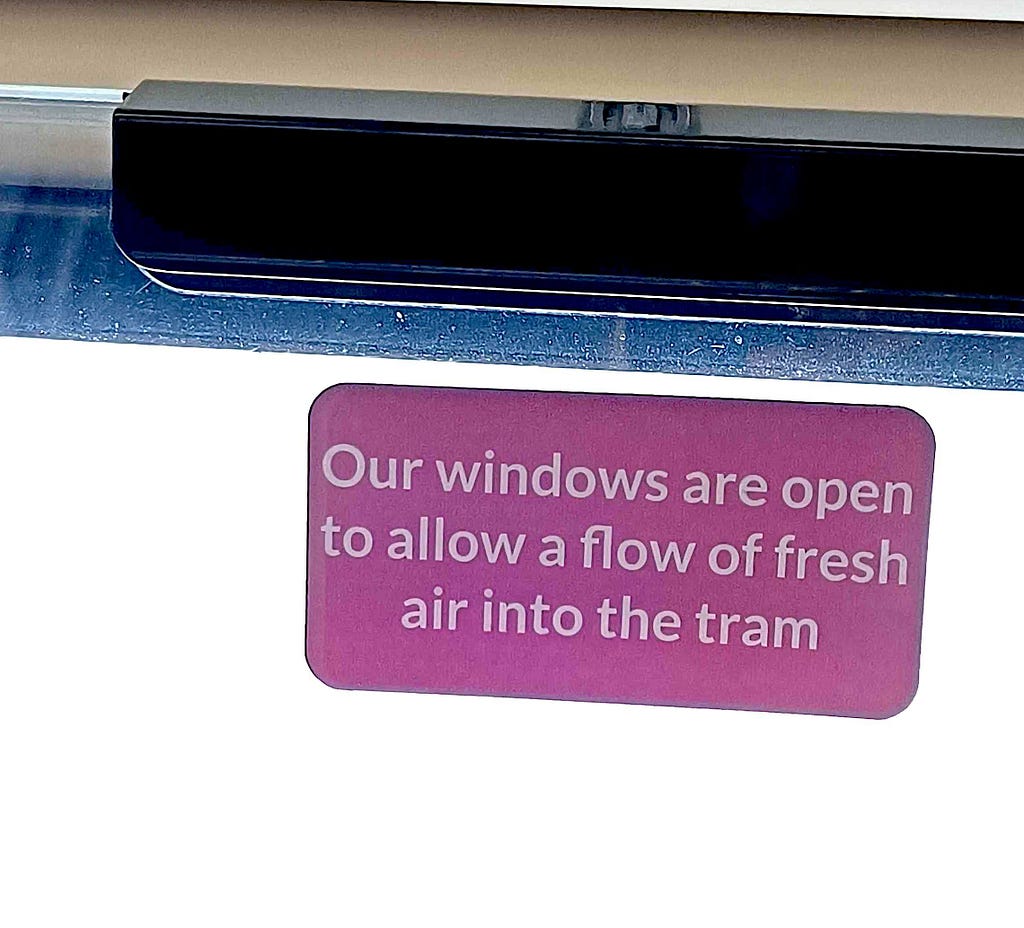 A picture of a sticker explaining why windows are open on a tram. The sticker says “Our windows are open to allow a flow of fresh air into the tram”