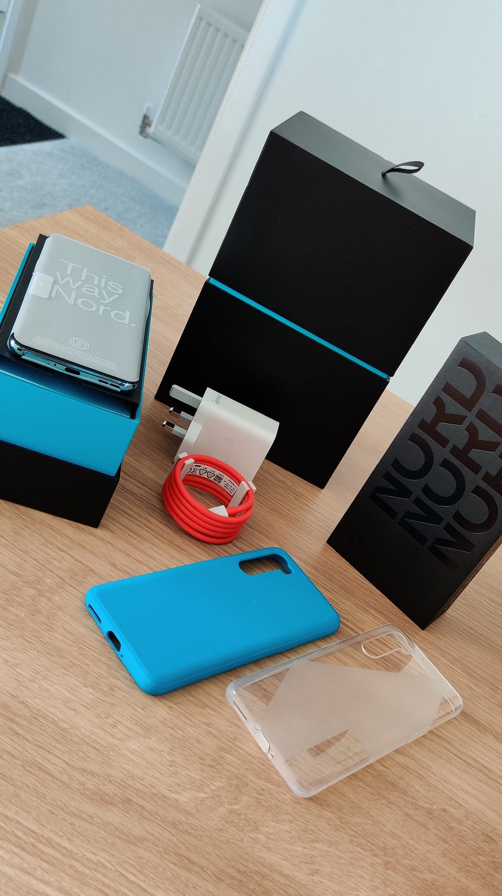 OnePlus Nord along with accessories such as charger and sandstone case.
