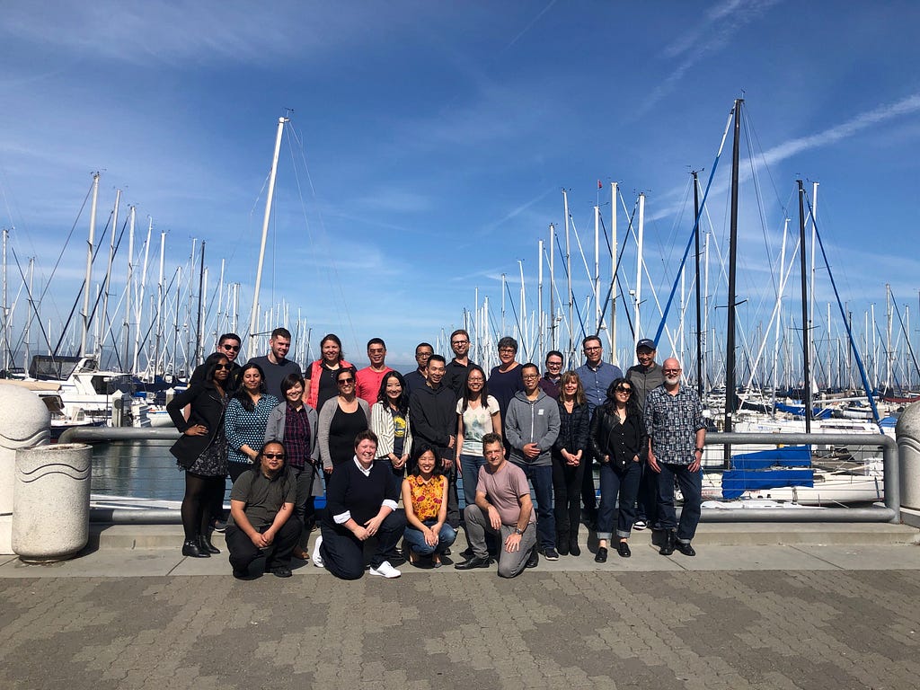 A picture of the Digital Services Team members smiling in the sun in front of some boats at the waterfront in San Francisco