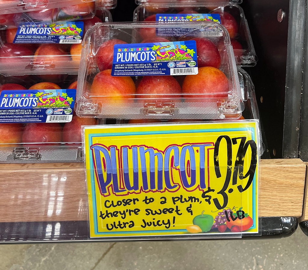 Product tag that says “Plumcot (closer to a plum, they’re sweet & ultra juicy!)”