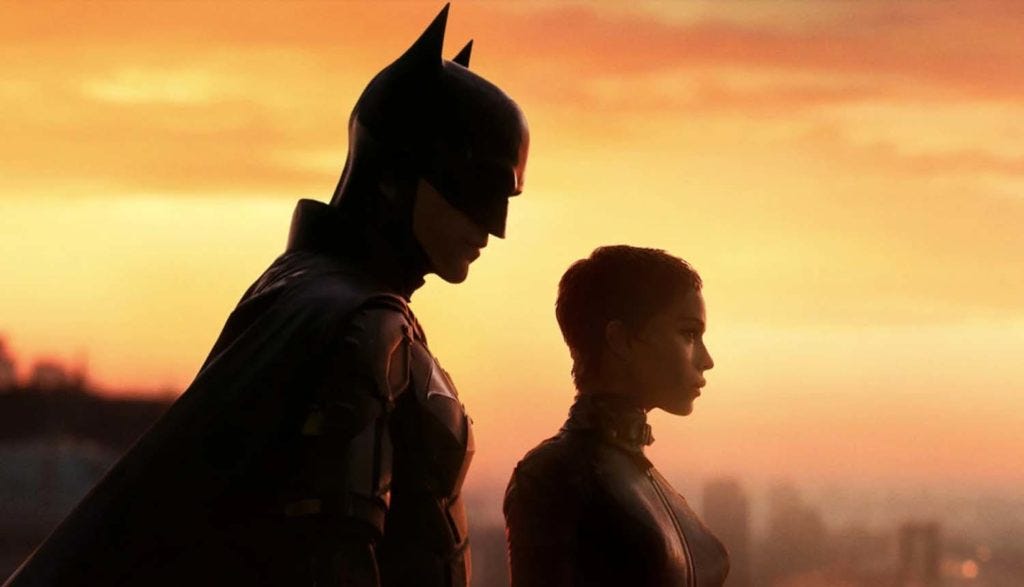 Against an orange sunset, Zoë Kravitz as Selina Kyle and Robert Pattinson as Batman are overlooking Gotham City.