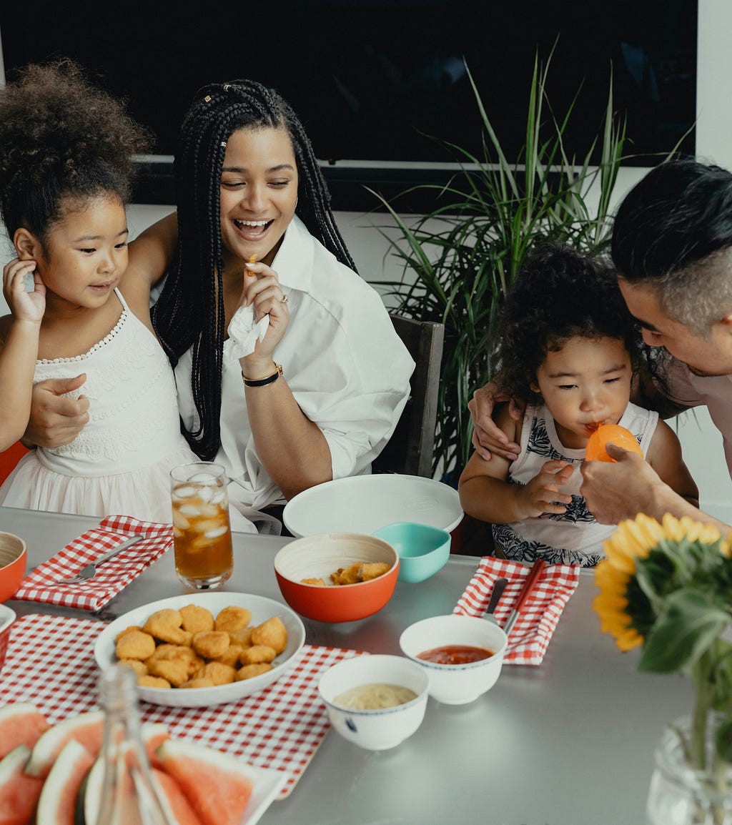 Woman sitting at dinner table with two children and partner