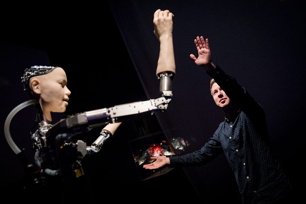 A person mirroring the movements of the humanoid robot Alter 3.