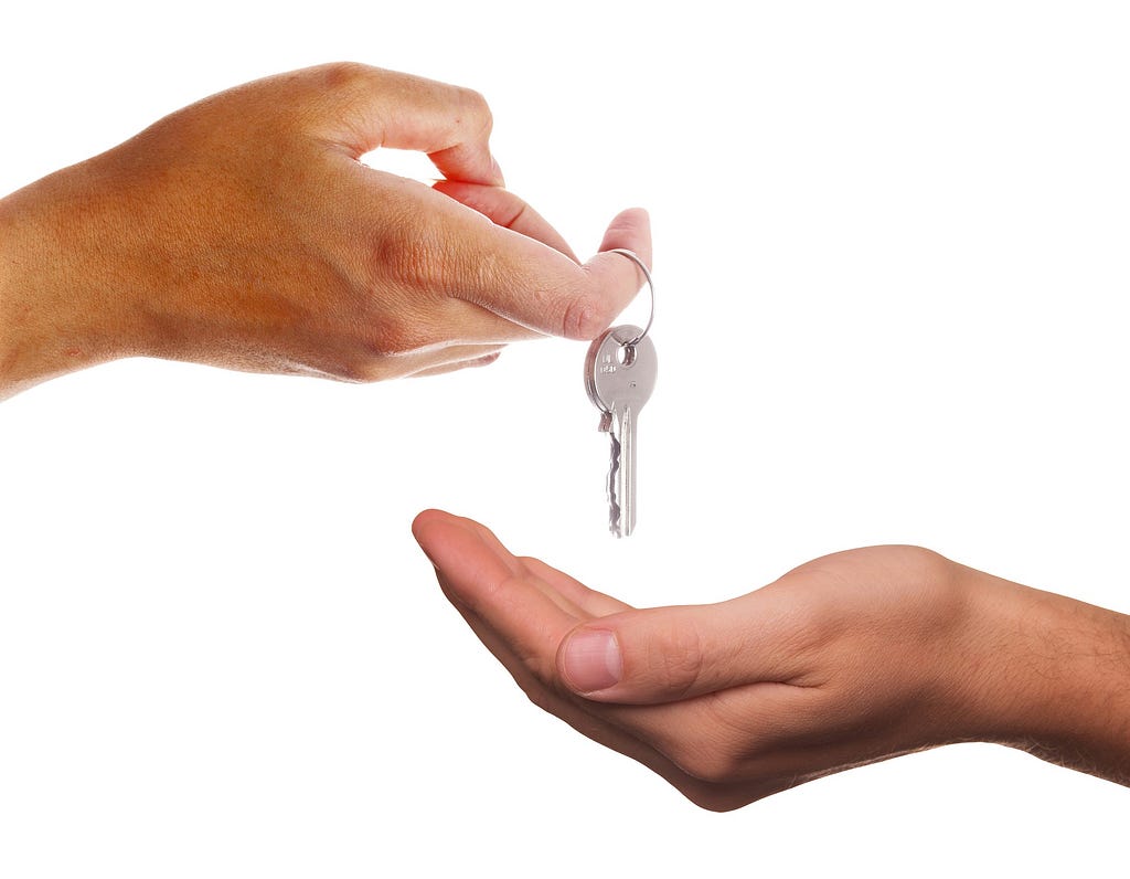 A set of keys is passed from one person’s hand to another’s.