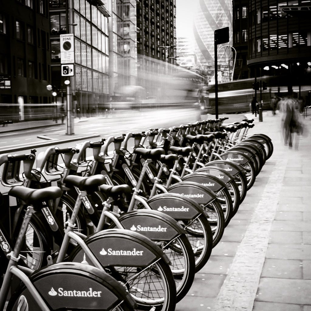Santander bike share rack of bikes in black and white with motion in the background blurred