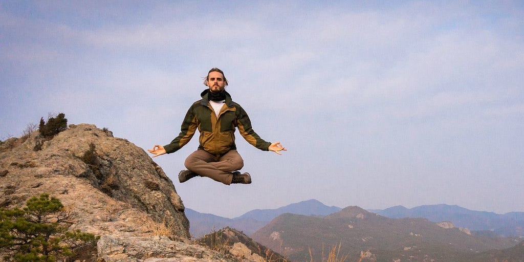 Man appearing to levitate above a mountain.