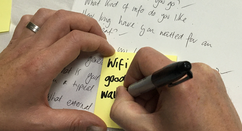 Participant writing user interview notes on a sticky note.