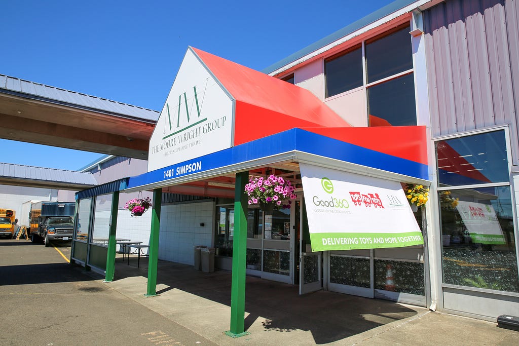 The entrance of The Moore Wright Group’s warehouse location. The side’s of the awning are red with a white front and the organization’s logo in green.