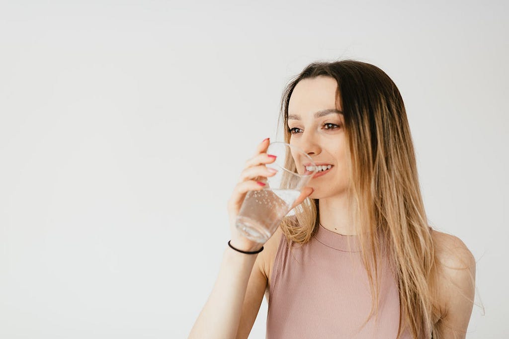 Delighted young woman drinking water from glass