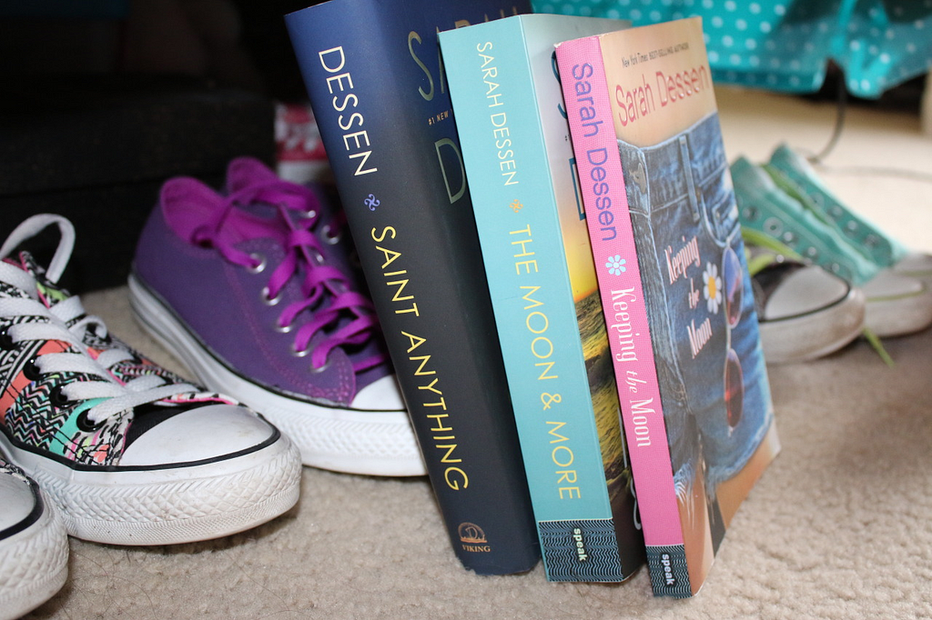 The books by author Sarah Dessen leaning against pairs of Converse shoes.