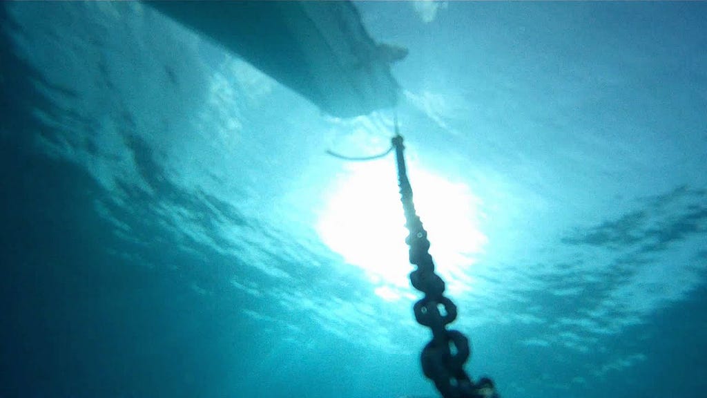 View of an anchor chain leading to a boar from underwater