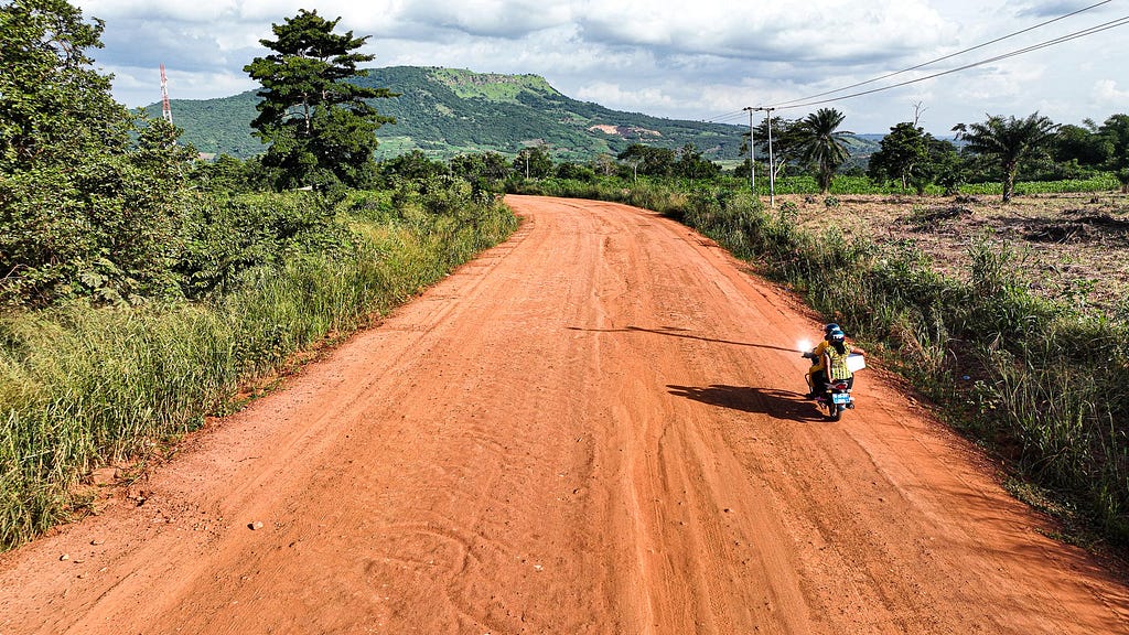 Judith on the back of a motorcycle on a dirt road.