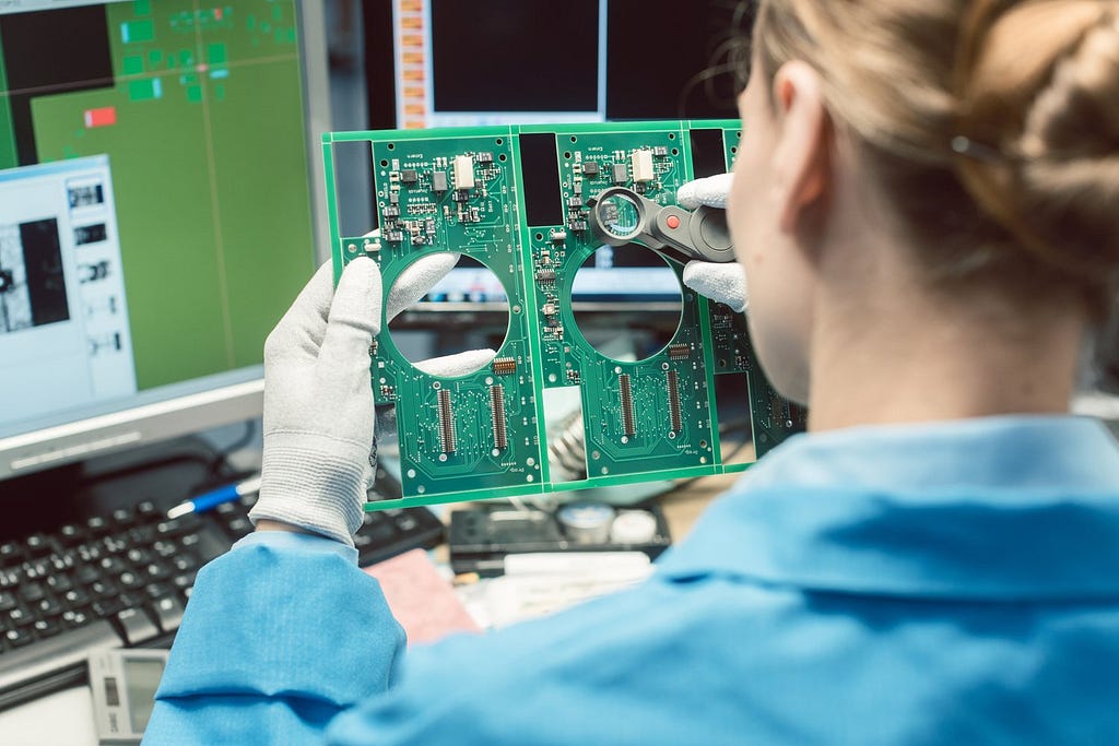 Engineer performs a manual visual inspection of some uniquely shaped circuit boards