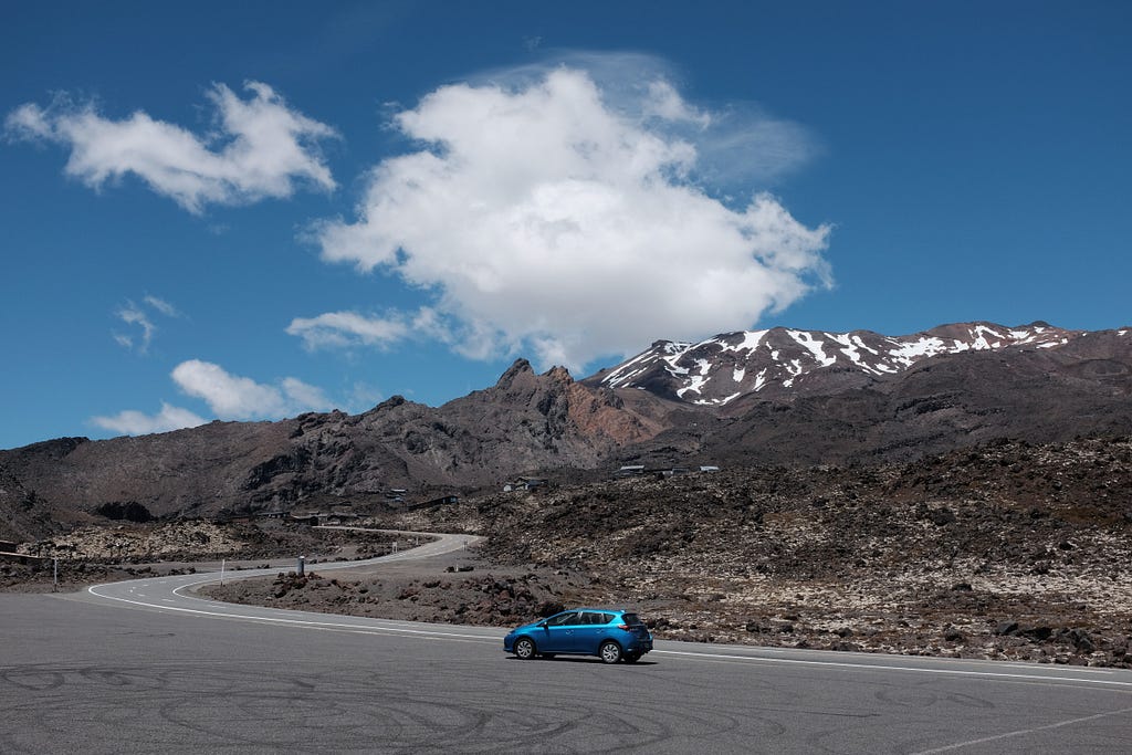 Blue car in front of mountains.