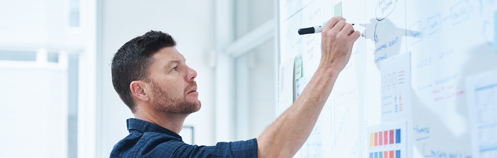 A man trying to brainstorm more ideas on a whiteboard