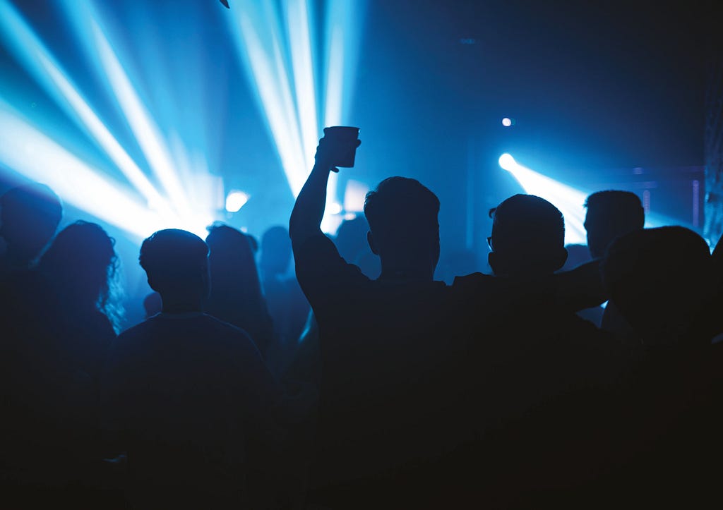 People holding drinks at a nightclub, blue strobe lights