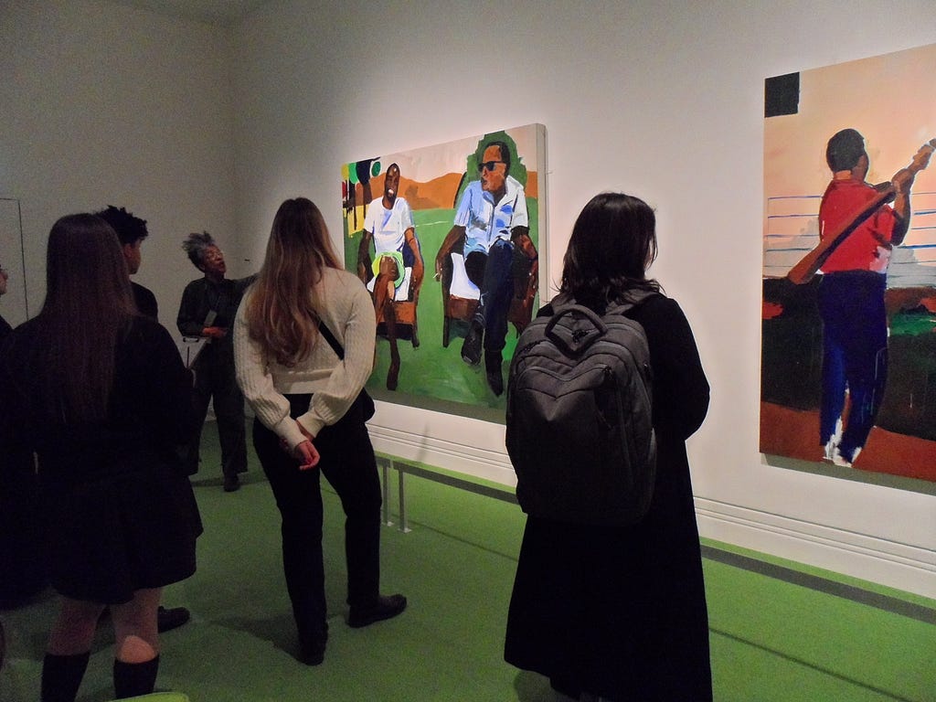 Visitors at The Time Is Always Now: Artists Reframe The Black Figure gather to reflect on paintings being displayed.