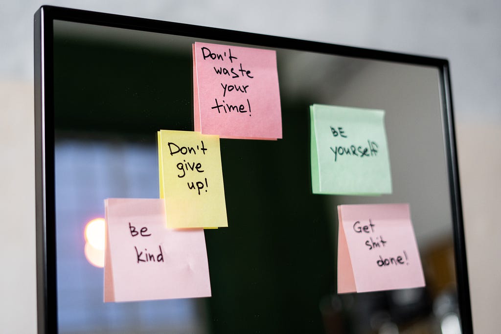 Sticky notes on a glass door, with a positive message on each note.