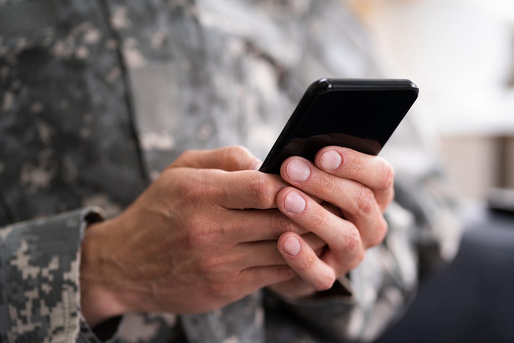Army soldier using smartphone.