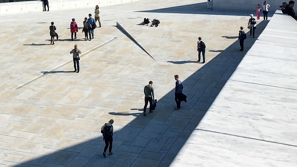 People walking in the shade during a sunny day.