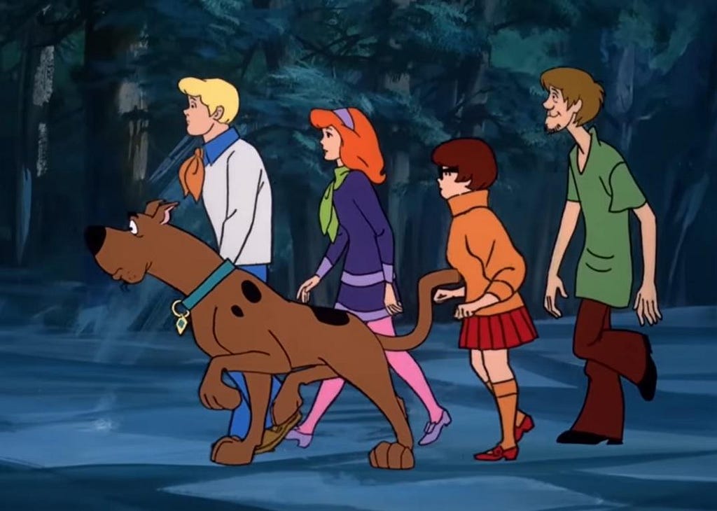 The Scooby-Doo Mystery Gang (including Fred, Scooby, Daphne, Velma, and Shaggy) walking through the woods.