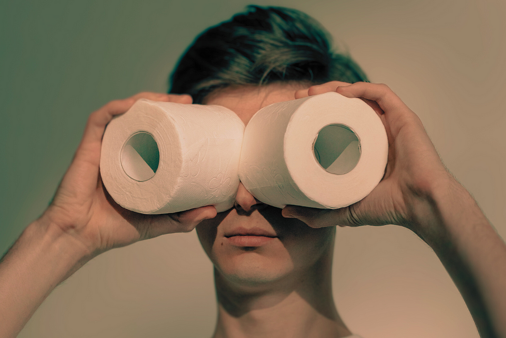 A man looking through toilet paper rolls.
