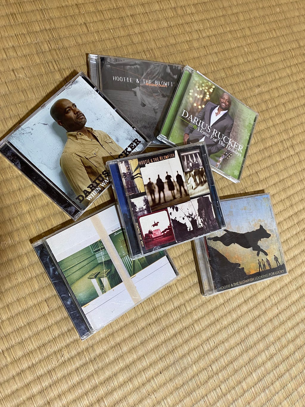 A pile of Hootie & the Blowfish CDs on a tatami mat floor.