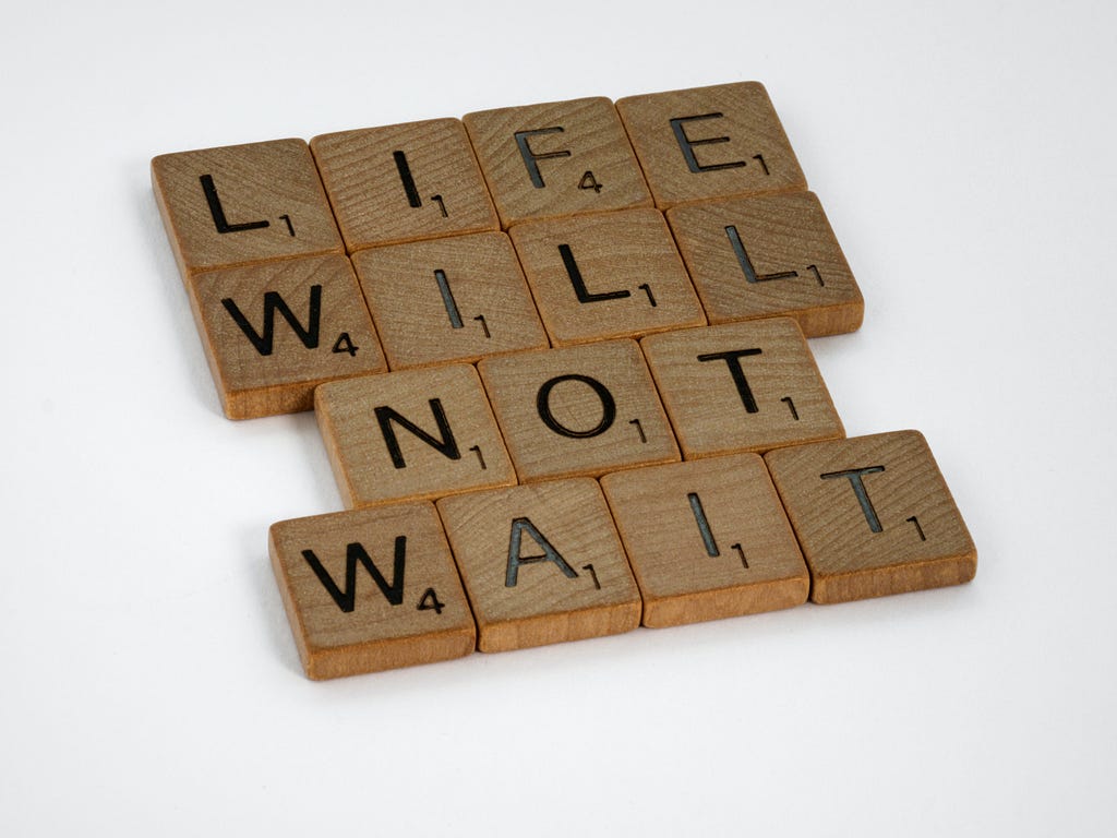 Wood tiles put together to form the text: “LIFE WILL NOT WAIT.”