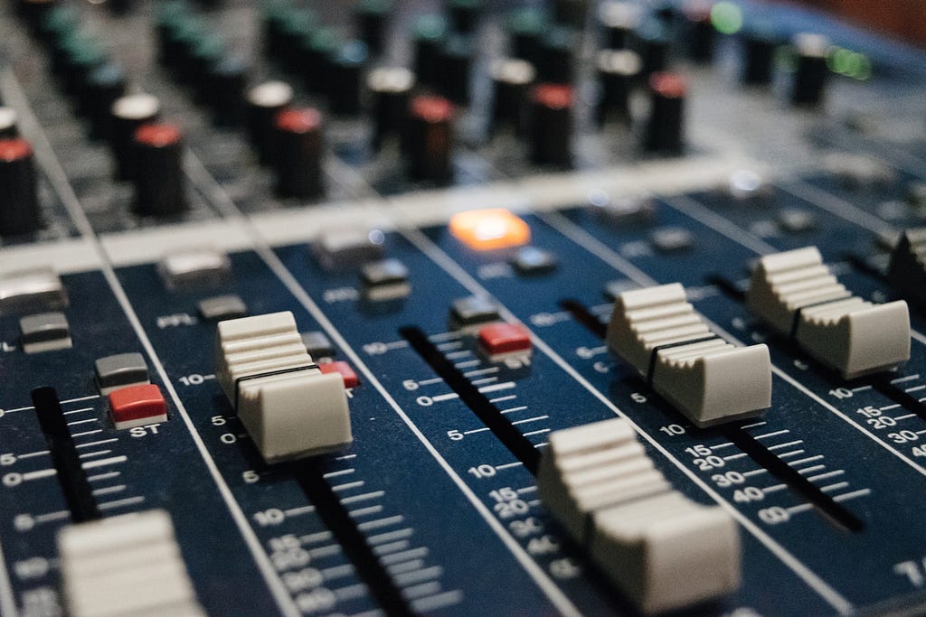 Knobs and faders on a music mixing panel.