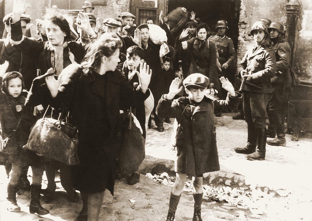 A roup of Polish Jews captured by German soldiers during the suppression of the Warsaw Ghetto Uprising (Poland). Some are women with raised hands. One is a little boy, also with hands raised.