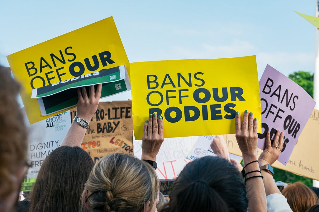 Pro-choice protesters gathered at a rally hold signs that read “Bans Off Our Bodies.” Photo by Gayatri Malhotra for Unsplash.