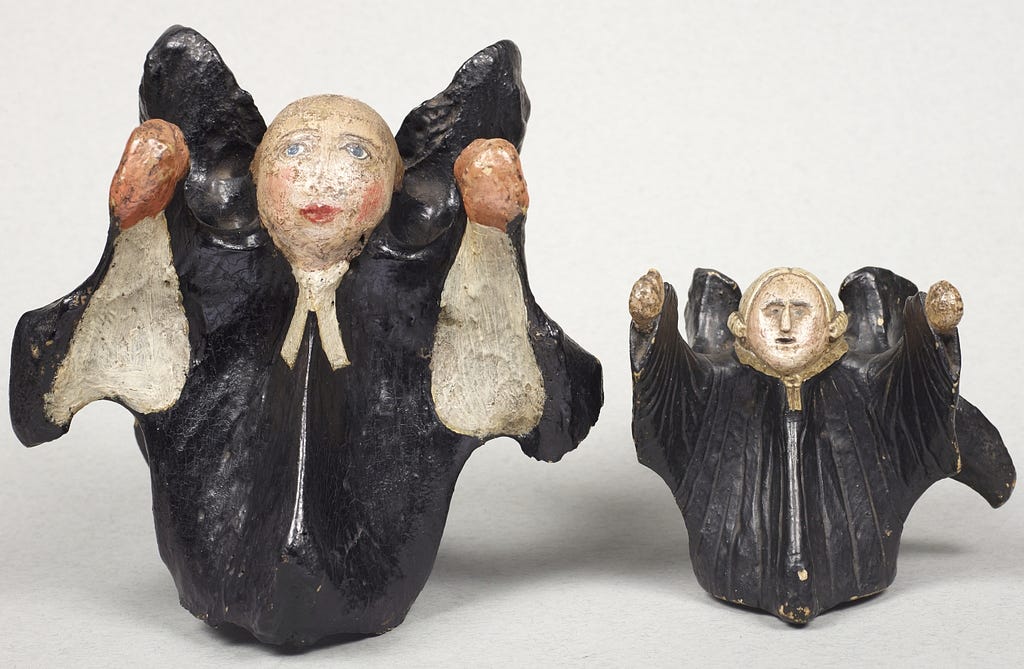 2 effigies- 1 large and 1 small- of the 18th-century Methodist leader John Wesley made out of horse vertebrae which have been hand painted to resemble the cleric in his black clergy robes giving a sermon.