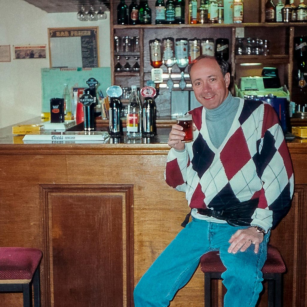 Harvey Blumenthal holding up a glass of beer at a pub in Oban
