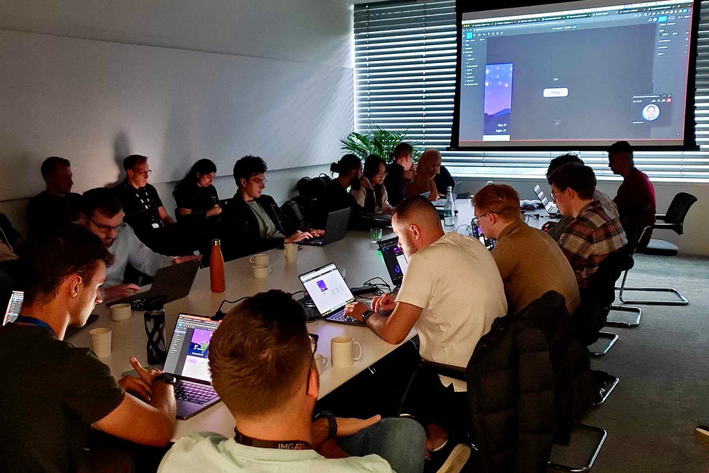 A group of people using their laptops to practice and learn Figma (a collaborative interface design tool) in a meeting room.