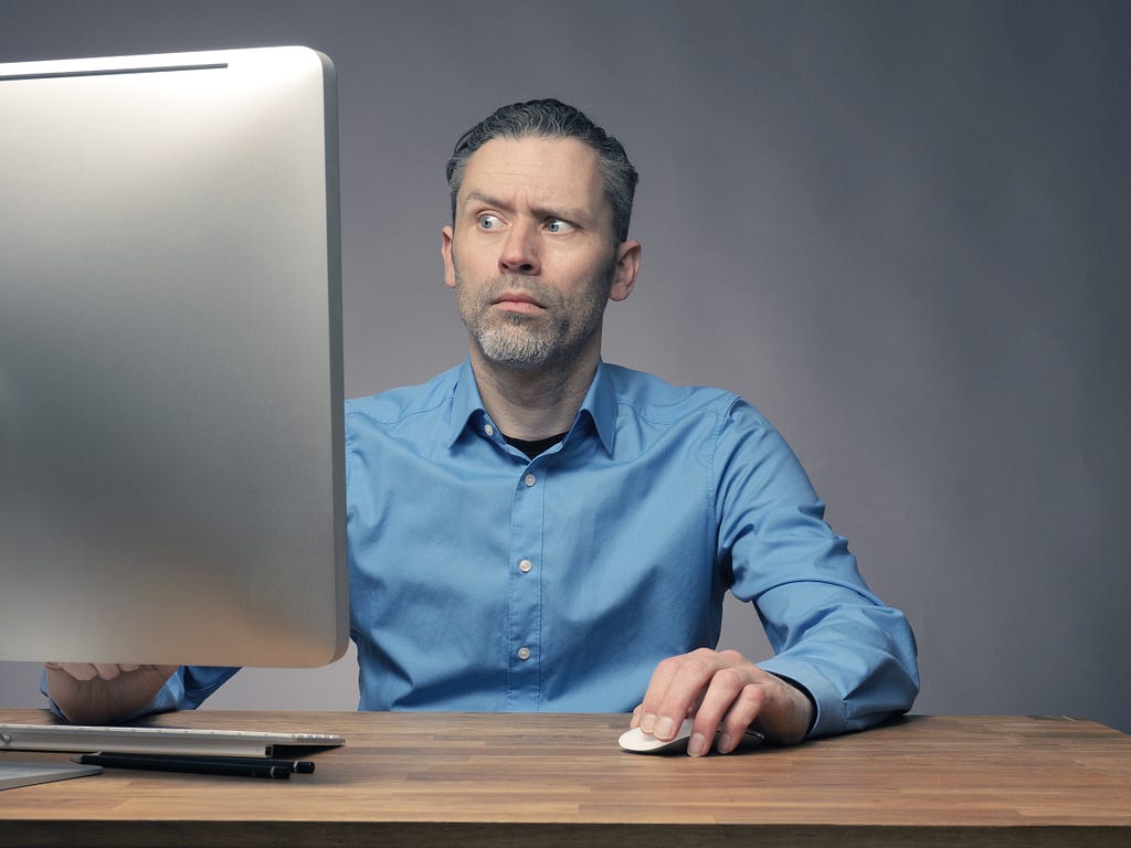 A man staring at a computer screen. One eyebrow is raised as if to say, “What the heck did I do and how do I undo it?”